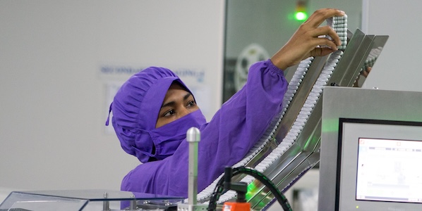 Worker in purple scrubs in a medicine manufacturing facility in Bangladesh