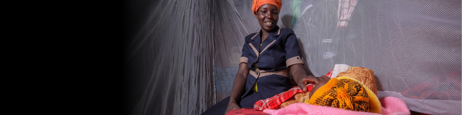 Mom and baby under a mosquito net (Credit: Flickr/PMI)