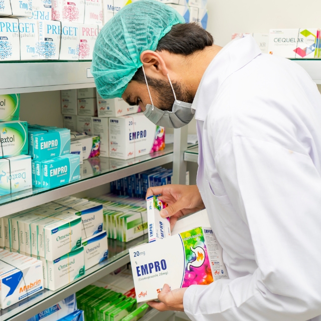 Pharmacist in Pakistan stocking shelves with medicines